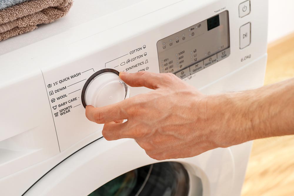 Hand som slår på tvättmaskinen